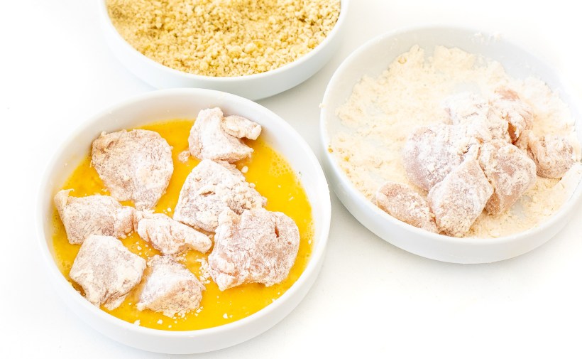dredging chicken pieces in eggs, flour and breadcrumbs